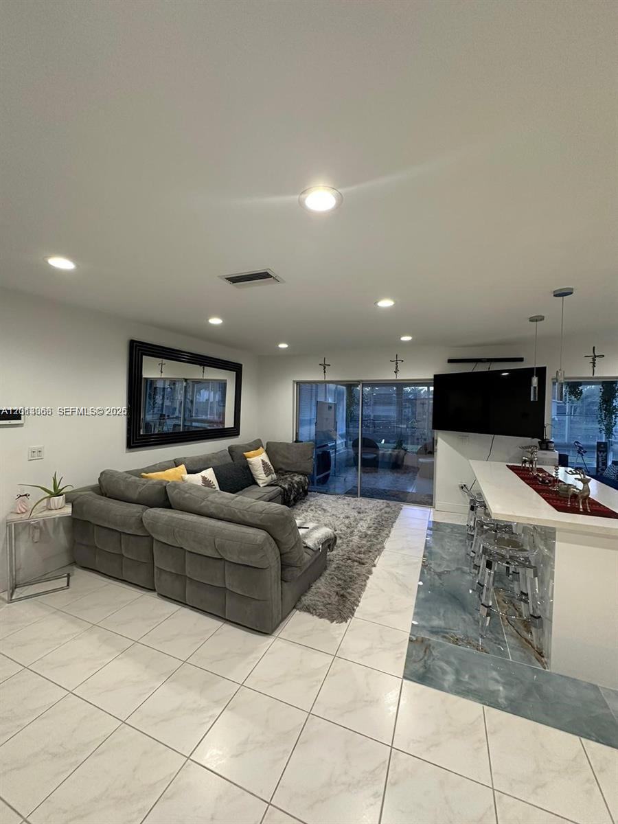 A living room with a gray sectional sofa, tiled floors, and a kitchen island — 9590 NW 24th Pl, Sunrise FL 33322, SUNRISE, FL
