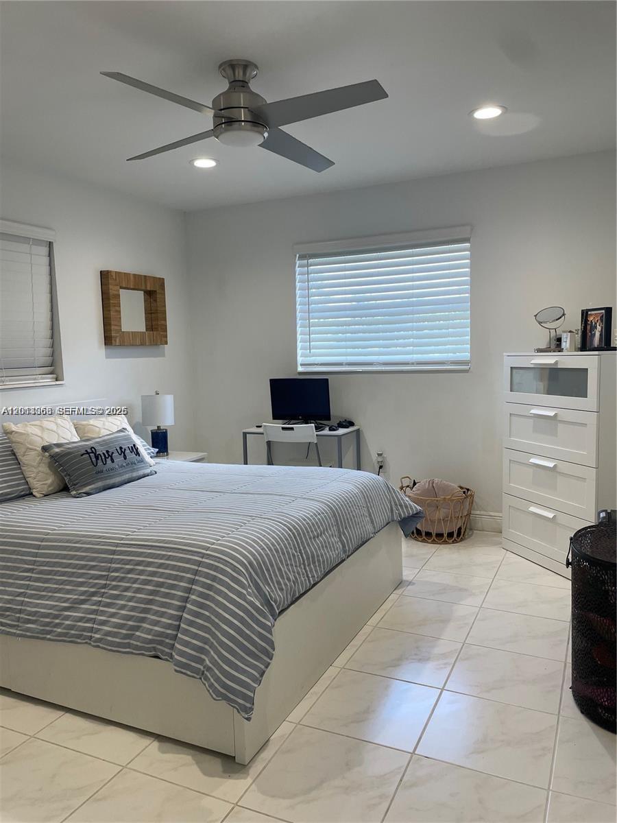 A bedroom features a bed with striped bedding, a desk, and a white dresser — 9590 NW 24th Pl, Sunrise FL 33322, SUNRISE, FL