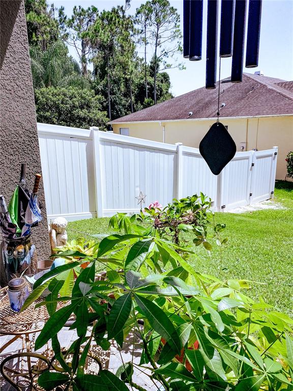 A patio view features a potted plant, a wind chime, and a white vinyl fence — 2379 PICKFORD CIRCLE, APOPKA, FL