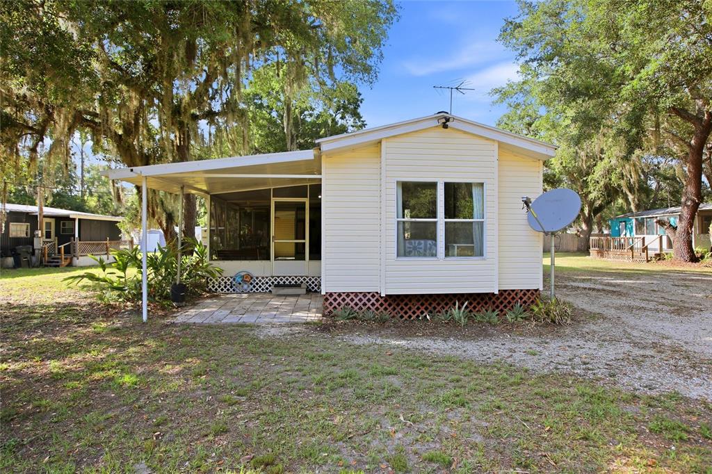 A light yellow mobile home features a screened-in porch and a gravel driveway — 3348 OMEC STREET, LAKE WALES, FL