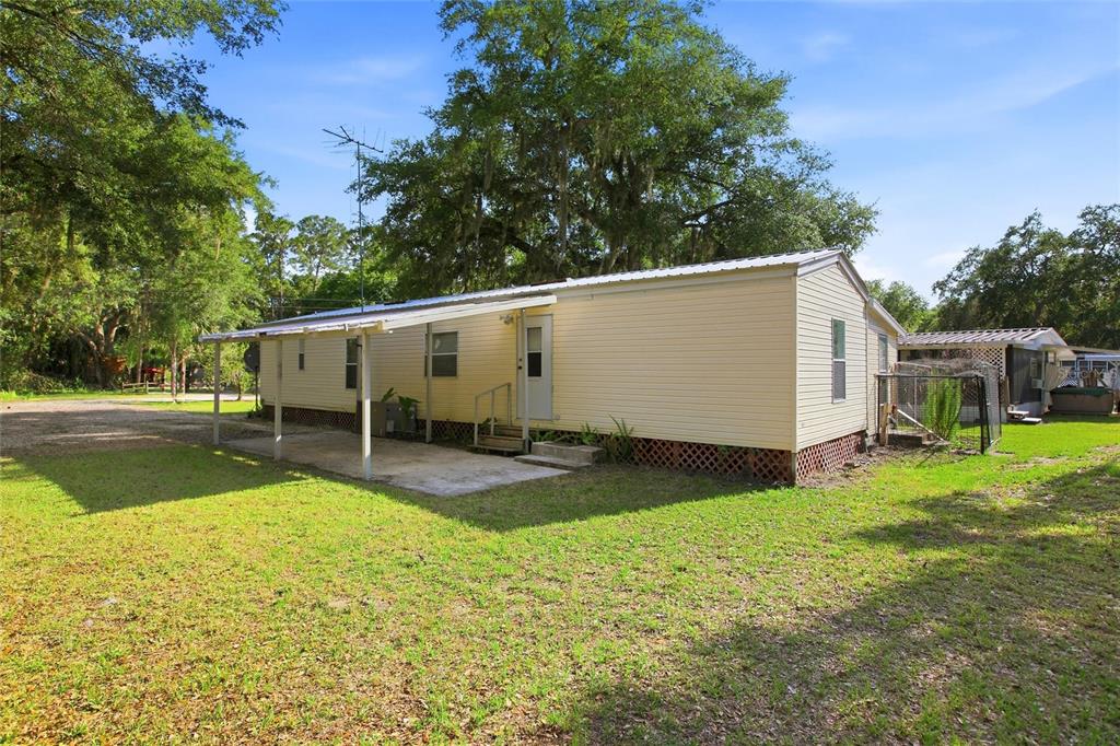 A light-yellow mobile home with a metal roof and a covered concrete patio area — 3348 OMEC STREET, LAKE WALES, FL
