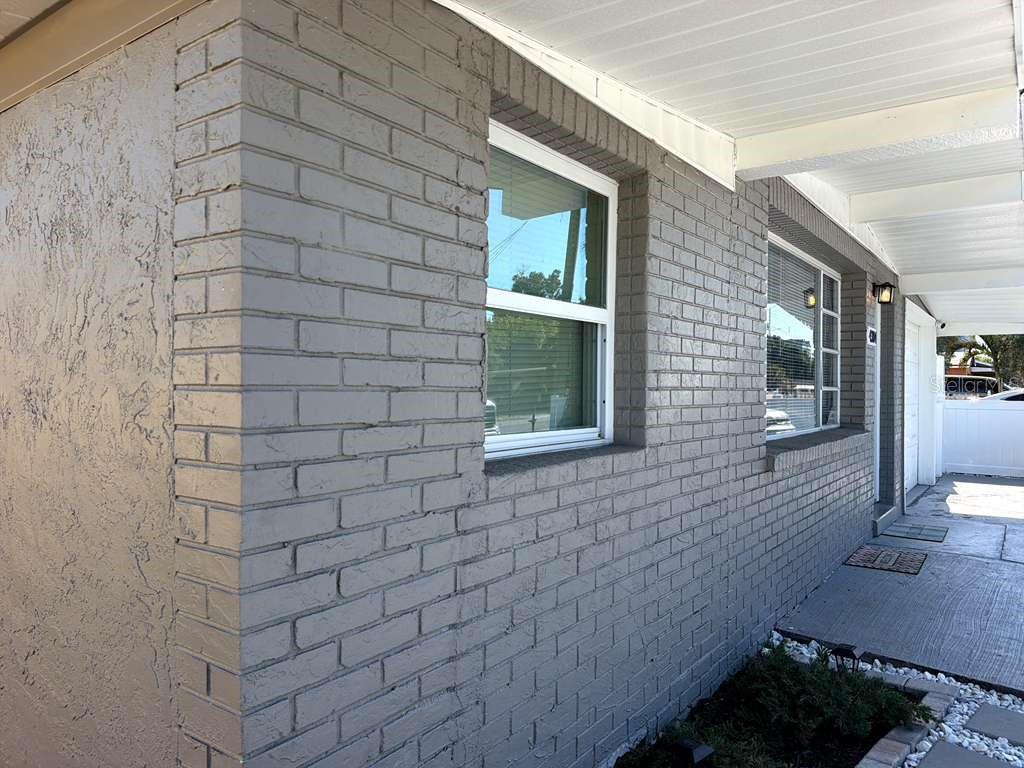 A gray painted brick exterior wall features two windows and a covered concrete walkway — 4304 W ARCH STREET, TAMPA, FL