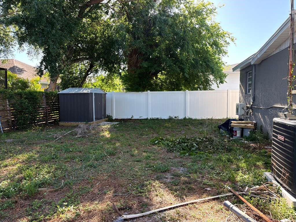 A backyard features a metal storage shed, a white vinyl fence, and an air conditioning unit — 4304 W ARCH STREET, TAMPA, FL