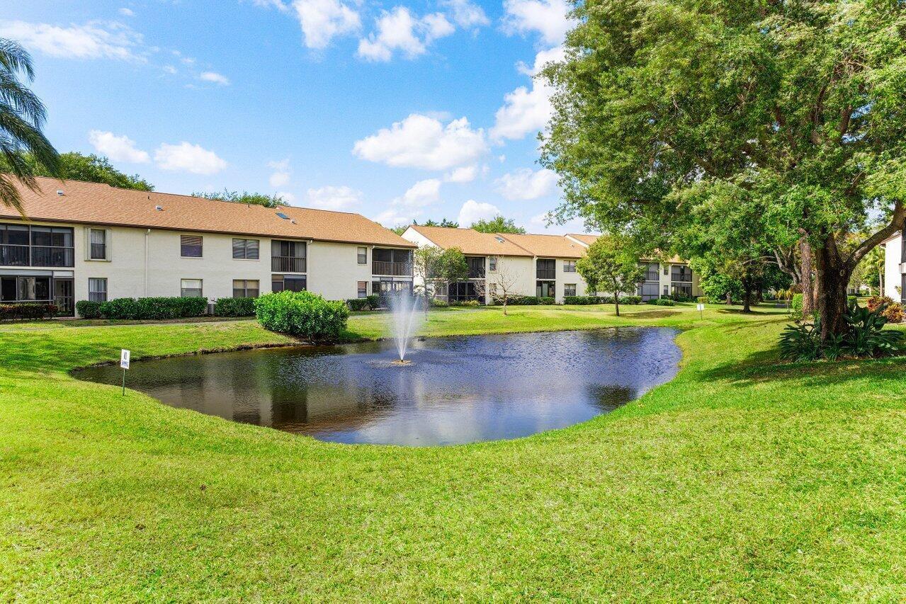 A pond with a fountain sits in front of multi-story apartment buildings and green lawns — 3362 Lucerne Park Drive, FL 33467, FL