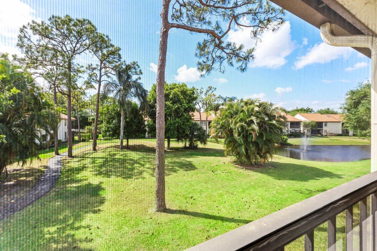A view from a screened balcony overlooking a grassy lawn, trees, and a small pond — 3362 Lucerne Park Drive, FL 33467, FL