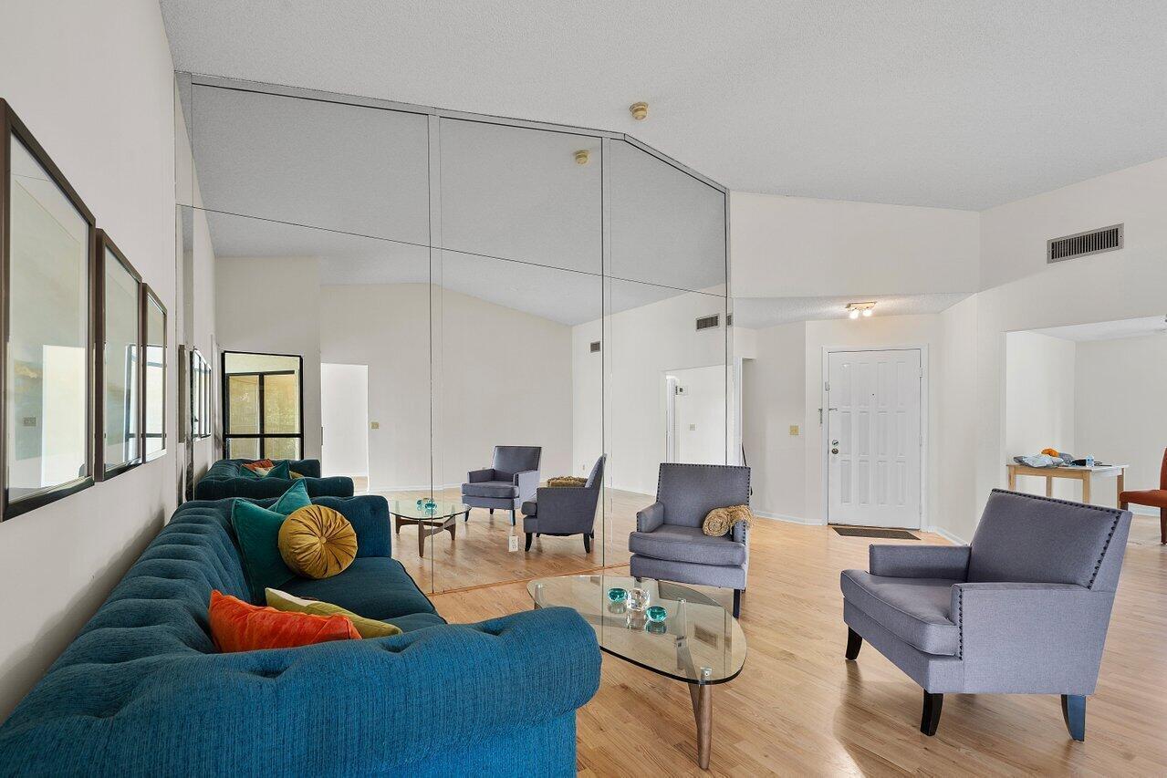 A living room features a blue tufted sofa, gray armchairs, and a large mirrored wall — 3362 Lucerne Park Drive, FL 33467, FL