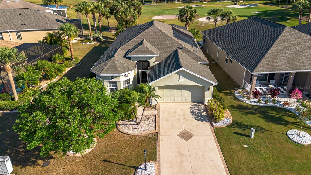 An aerial view shows a single-story house with a garage, driveway, and surrounding landscaping — 1038 EMERALD DUNES DRIVE, SUN CITY CENTER, FL