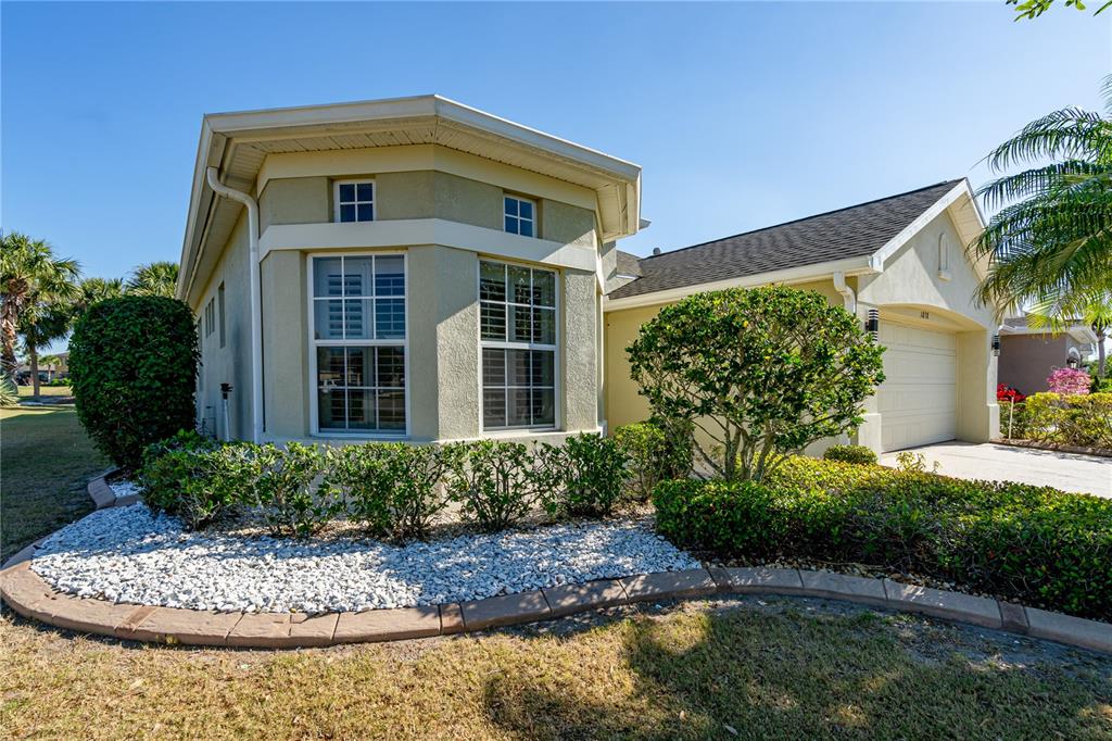 A single-story house with a beige stucco exterior, a two-car garage, and landscaped front yard — 1038 EMERALD DUNES DRIVE, SUN CITY CENTER, FL