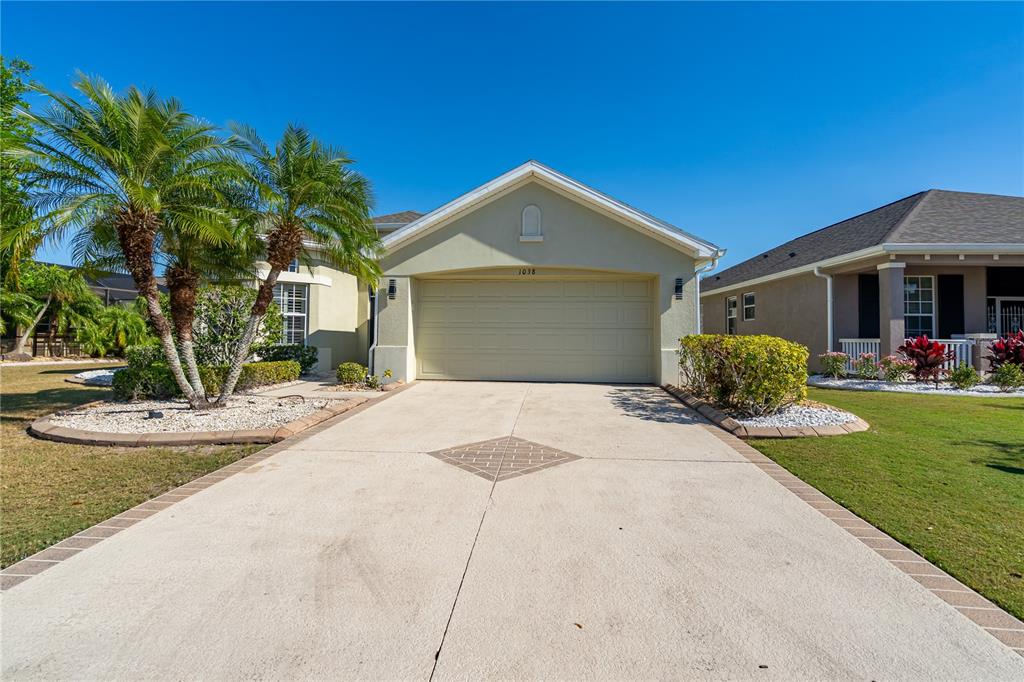 A single-story house with a beige exterior, a two-car garage, and a paved driveway — 1038 EMERALD DUNES DRIVE, SUN CITY CENTER, FL