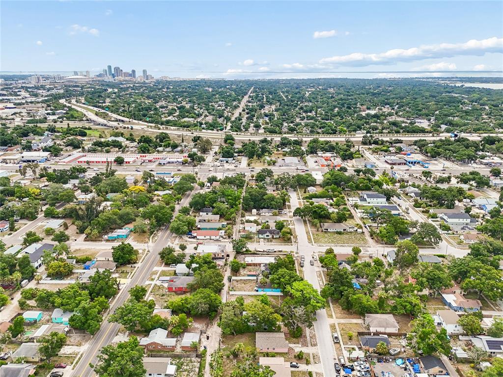 An aerial view shows a residential neighborhood with trees, houses, and a distant city skyline — 3603 16TH AVENUE S, ST PETERSBURG, FL