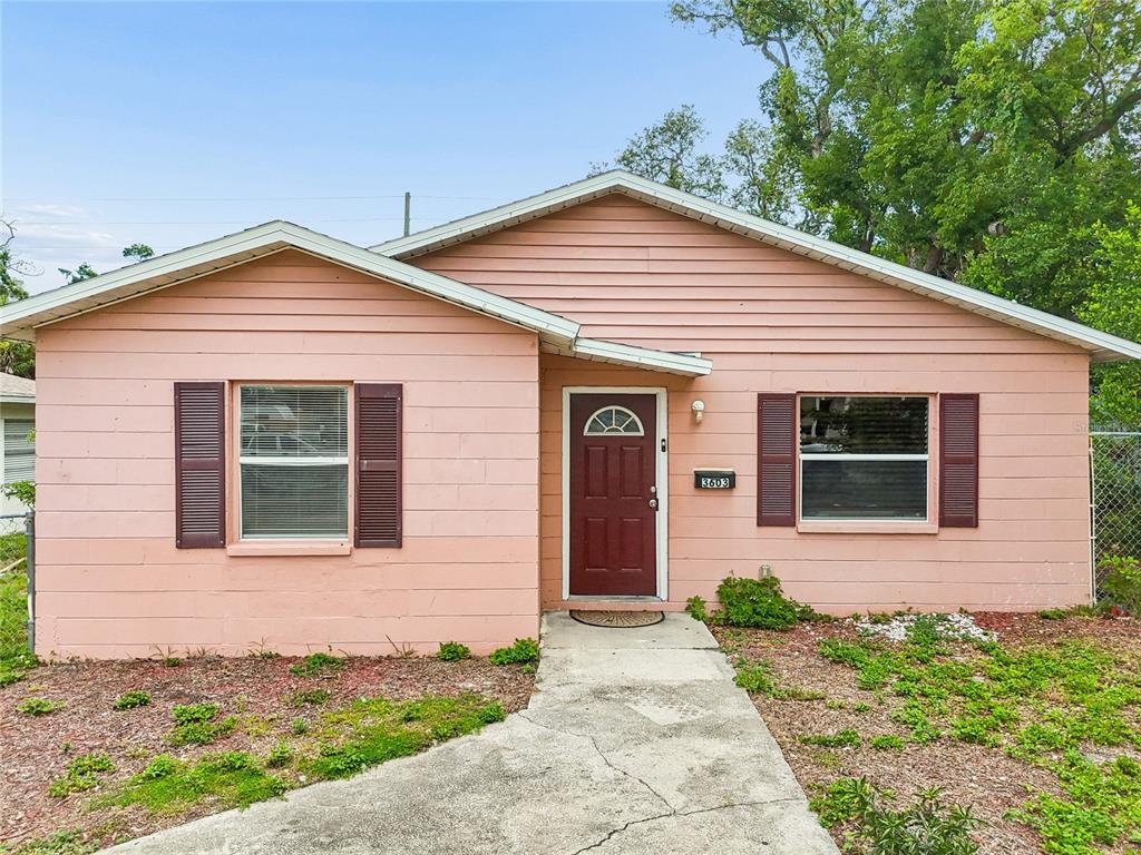 A single-story house with pink horizontal siding, a dark red door, and brown shutters — 3603 16TH AVENUE S, ST PETERSBURG, FL