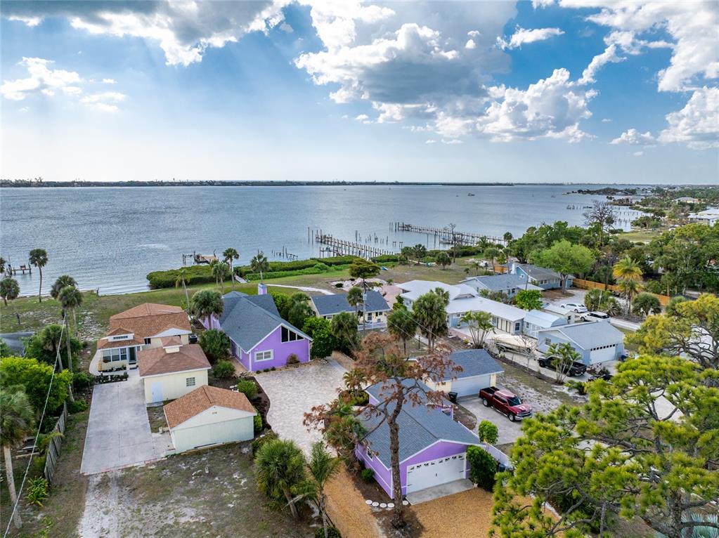 An aerial view shows several houses near a large body of water with wooden docks — 720 S MCCALL ROAD, ENGLEWOOD, FL