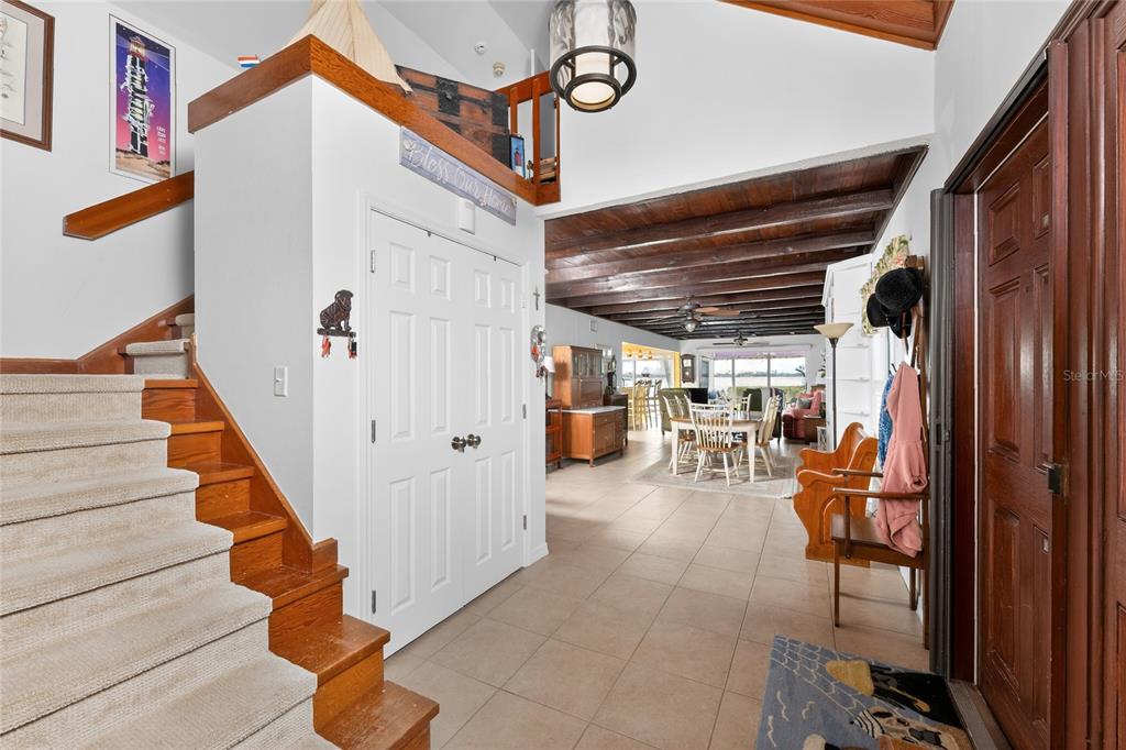An entryway features a carpeted staircase, a white door, and a view into a dining area — 720 S MCCALL ROAD, ENGLEWOOD, FL