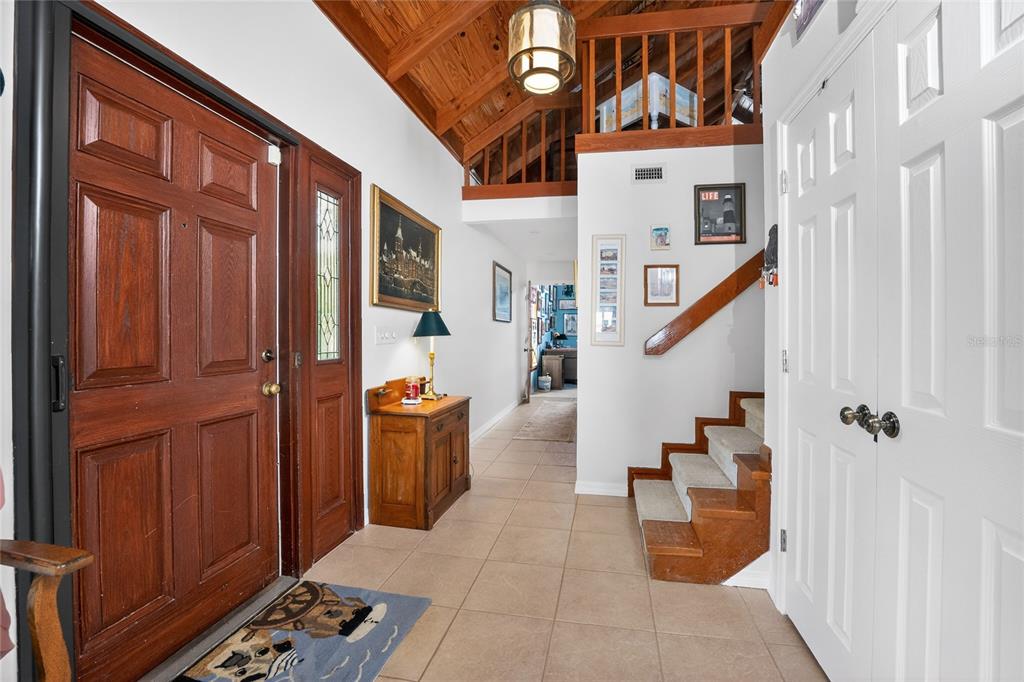 An entryway features a wooden front door, tiled floor, staircase, and a vaulted wood ceiling — 720 S MCCALL ROAD, ENGLEWOOD, FL