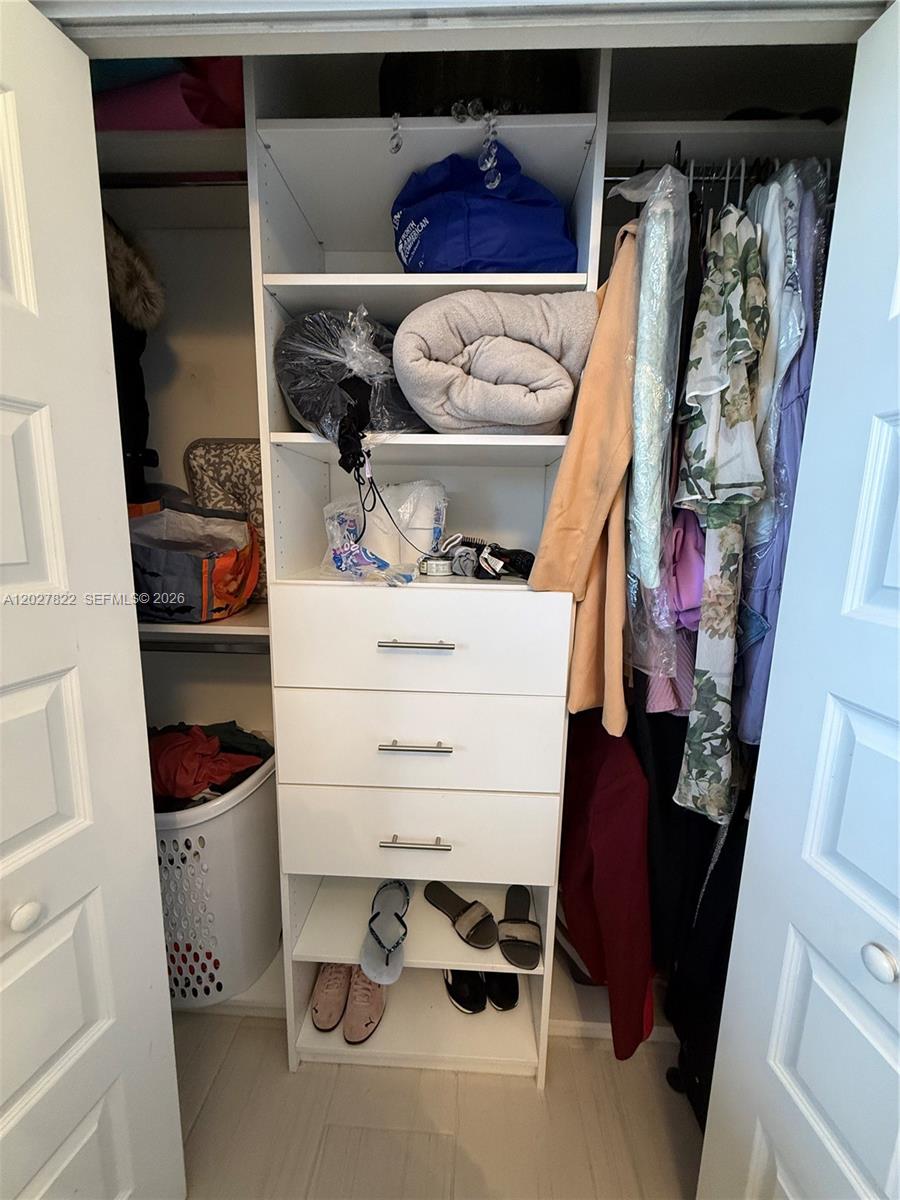 A reach-in closet features white shelving, a three-drawer unit, and hanging space for clothes — 7815 NW 104th Ave # 32, Doral FL 33178, DORAL, FL