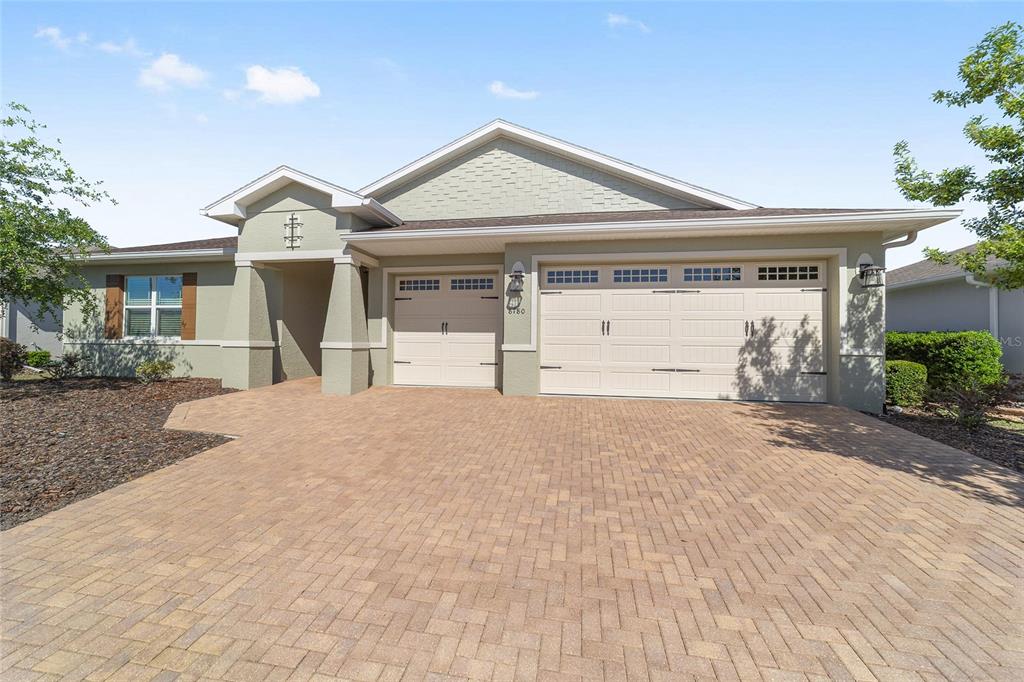 A single-story house with a paved driveway, two-car garage, and light green exterior siding — 8780 SW 93RD CIRCLE, OCALA, FL