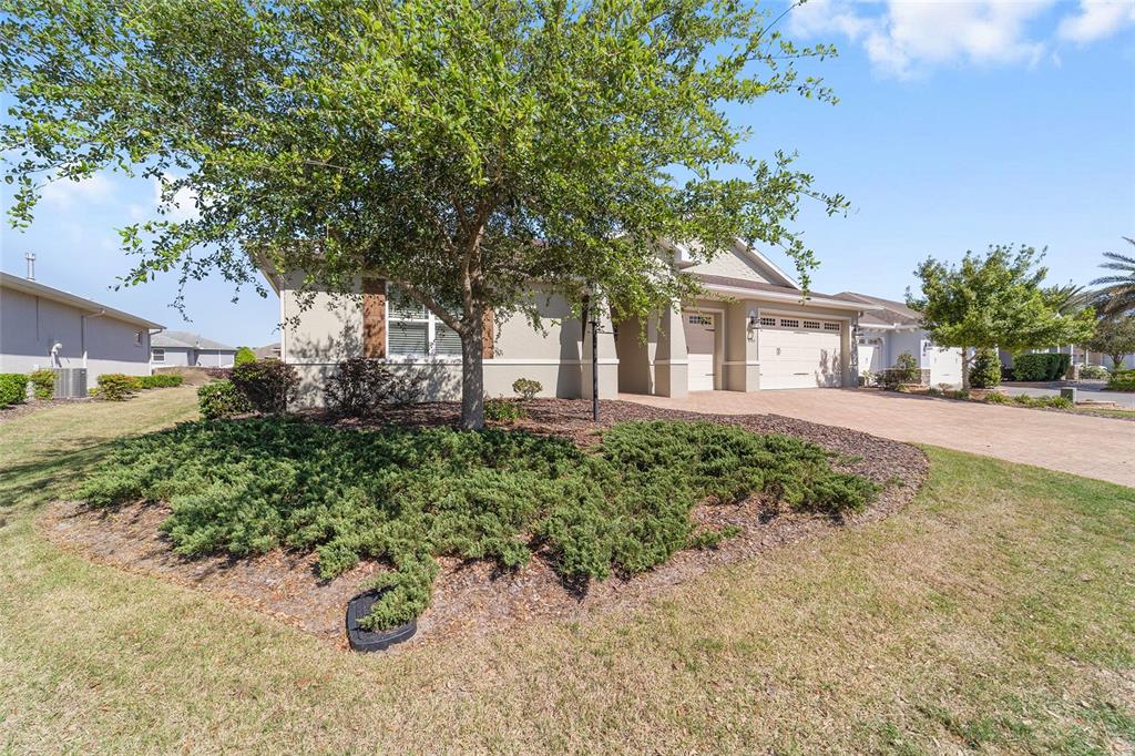 A single-story house with a beige exterior, a paved driveway, and a landscaped front yard — 8780 SW 93RD CIRCLE, OCALA, FL