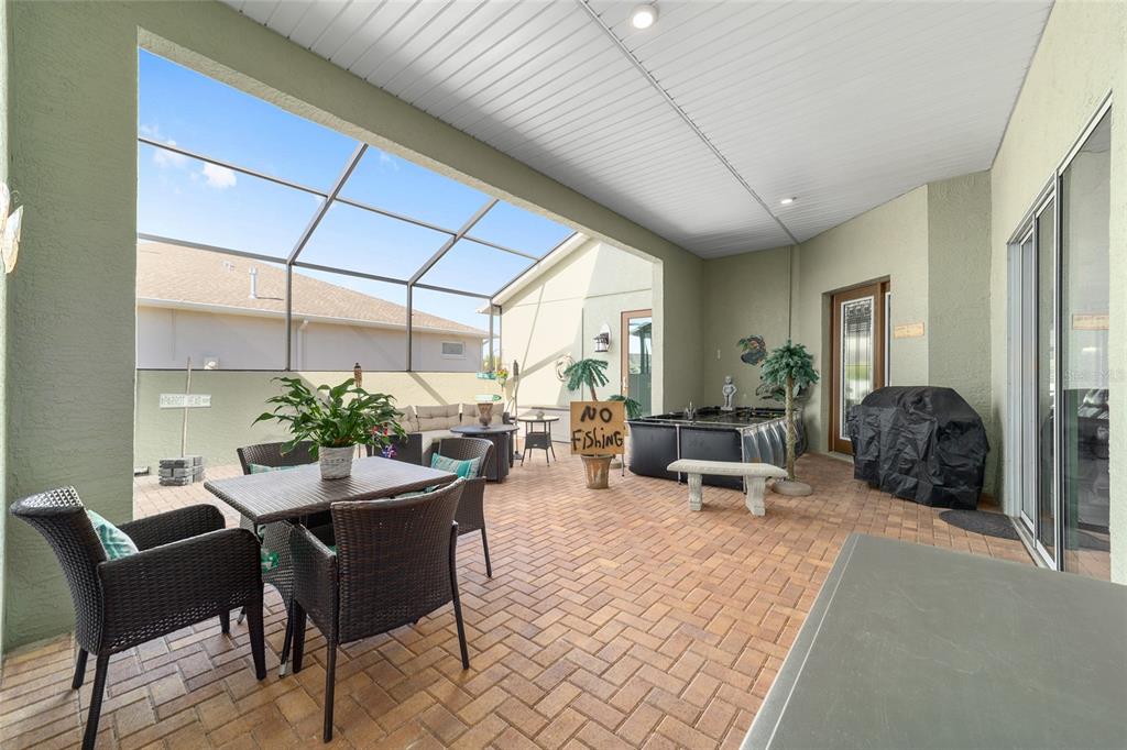 A covered patio with brick pavers, a screened enclosure, outdoor furniture, and a small pool — 8780 SW 93RD CIRCLE, OCALA, FL