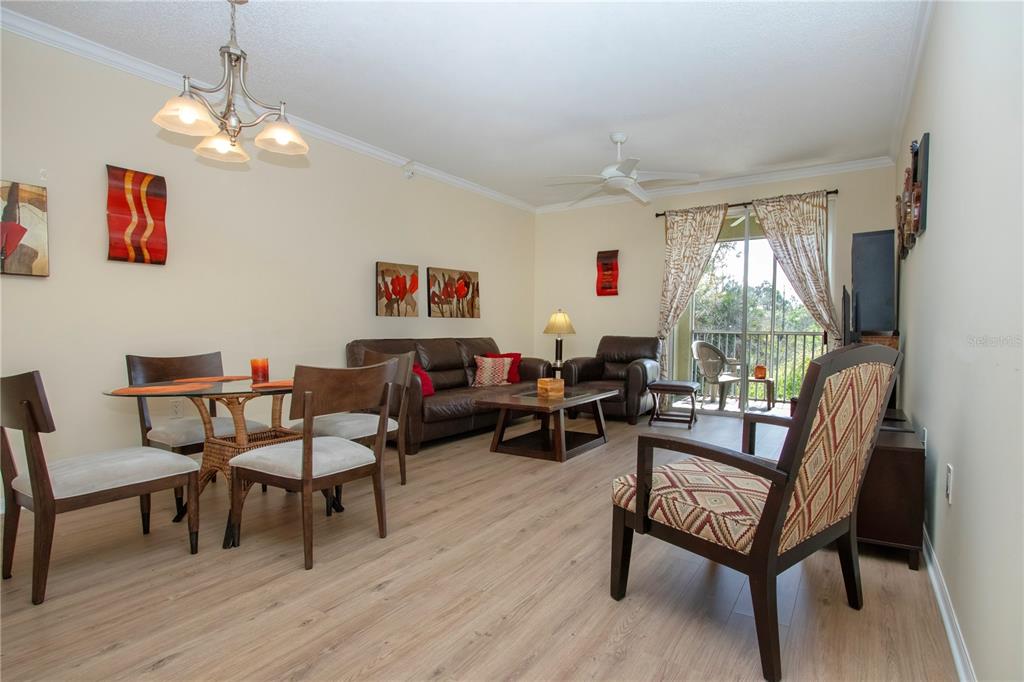 A living and dining room features wood-look flooring, a ceiling fan, and a sliding glass door — 5711 BENTGRASS DRIVE UNIT 19-202, SARASOTA, FL