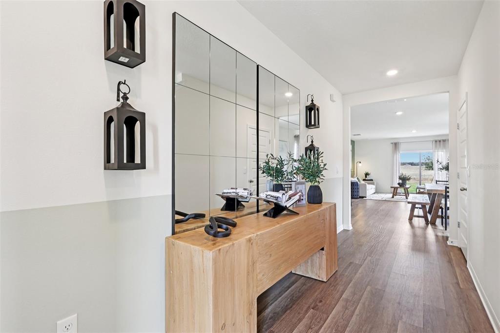 A wooden console table sits beneath a large grid mirror in a bright, modern entryway — 4930 KATRINA DRIVE, HAINES CITY, FL