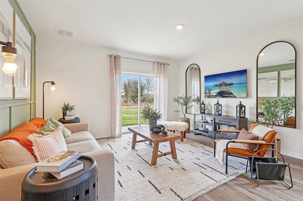 A living room features a beige sofa, wooden coffee table, armchair, and a wall-mounted television — 4930 KATRINA DRIVE, HAINES CITY, FL