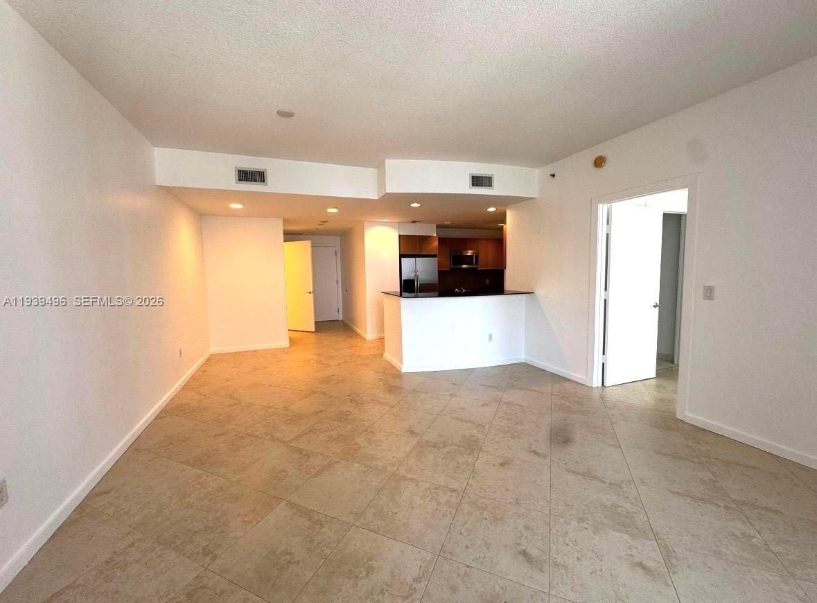 An open-concept living area features tile flooring, a kitchen island, and white walls — 1060 BRICKELL AV # 2603, Miami FL 33131, MIAMI, FL