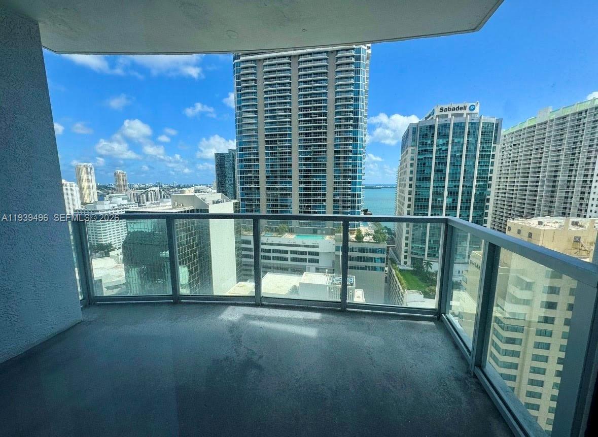 A balcony with a glass railing overlooks a city skyline and a body of water — 1060 BRICKELL AV # 2603, Miami FL 33131, MIAMI, FL