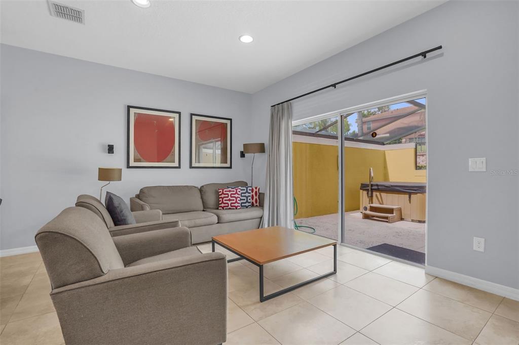 A living room with tile floors, neutral walls, and a sliding glass door to a patio — 3043 WHITE ORCHID ROAD, KISSIMMEE, FL