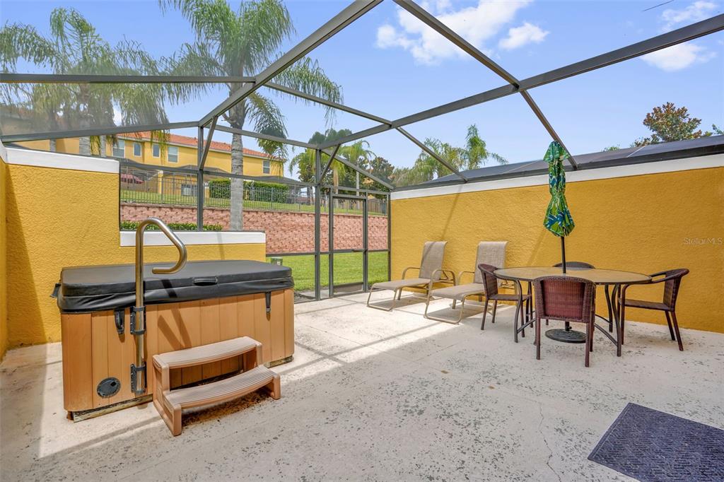A screened-in patio features a hot tub, lounge chairs, and a dining set — 3043 WHITE ORCHID ROAD, KISSIMMEE, FL