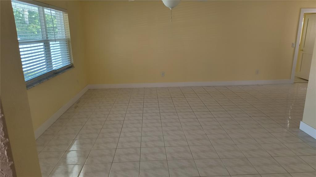 An empty room with yellow walls, white tile flooring, and a window with blinds — 3005 GULF BOULEVARD, BELLEAIR BEACH, FL