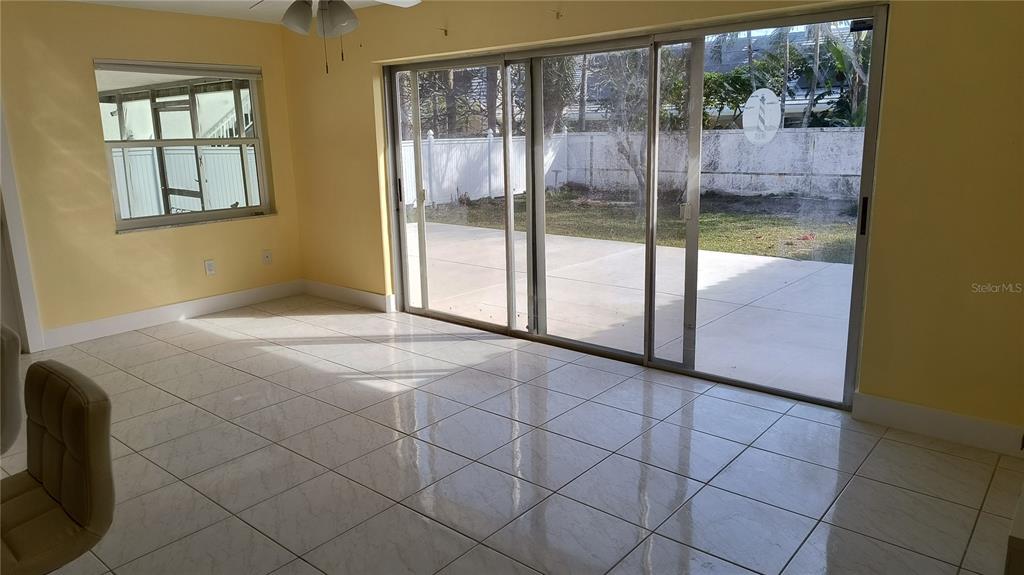 A bright room with yellow walls, tile flooring, and sliding glass doors leading to a patio — 3005 GULF BOULEVARD, BELLEAIR BEACH, FL