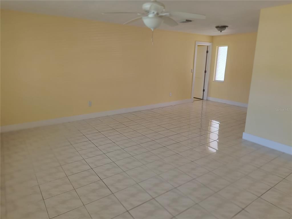 An empty room with yellow walls, white tile flooring, and a ceiling fan — 3005 GULF BOULEVARD, BELLEAIR BEACH, FL