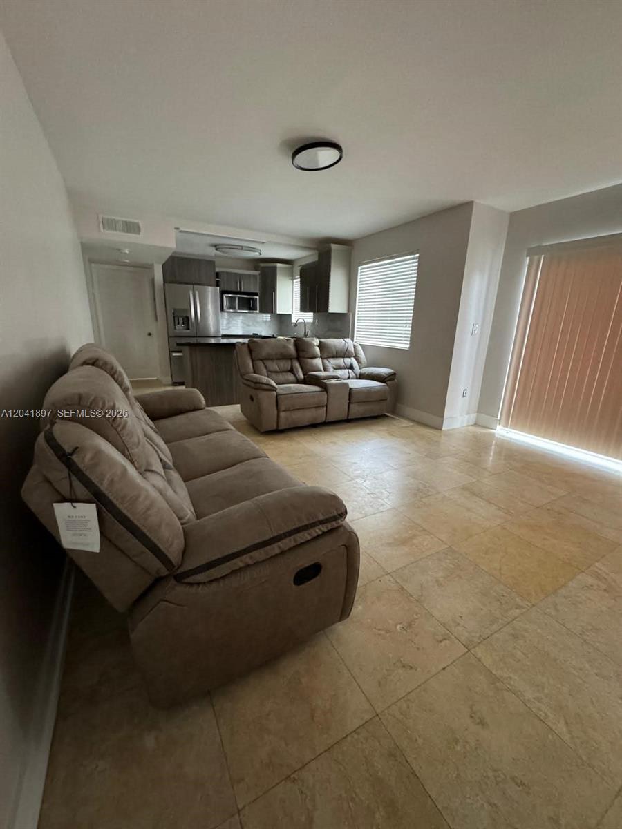 A living room with tile flooring features two brown reclining sofas and an open kitchen — 6200 SW 131st Ct # 201, Miami FL 33183, MIAMI, FL