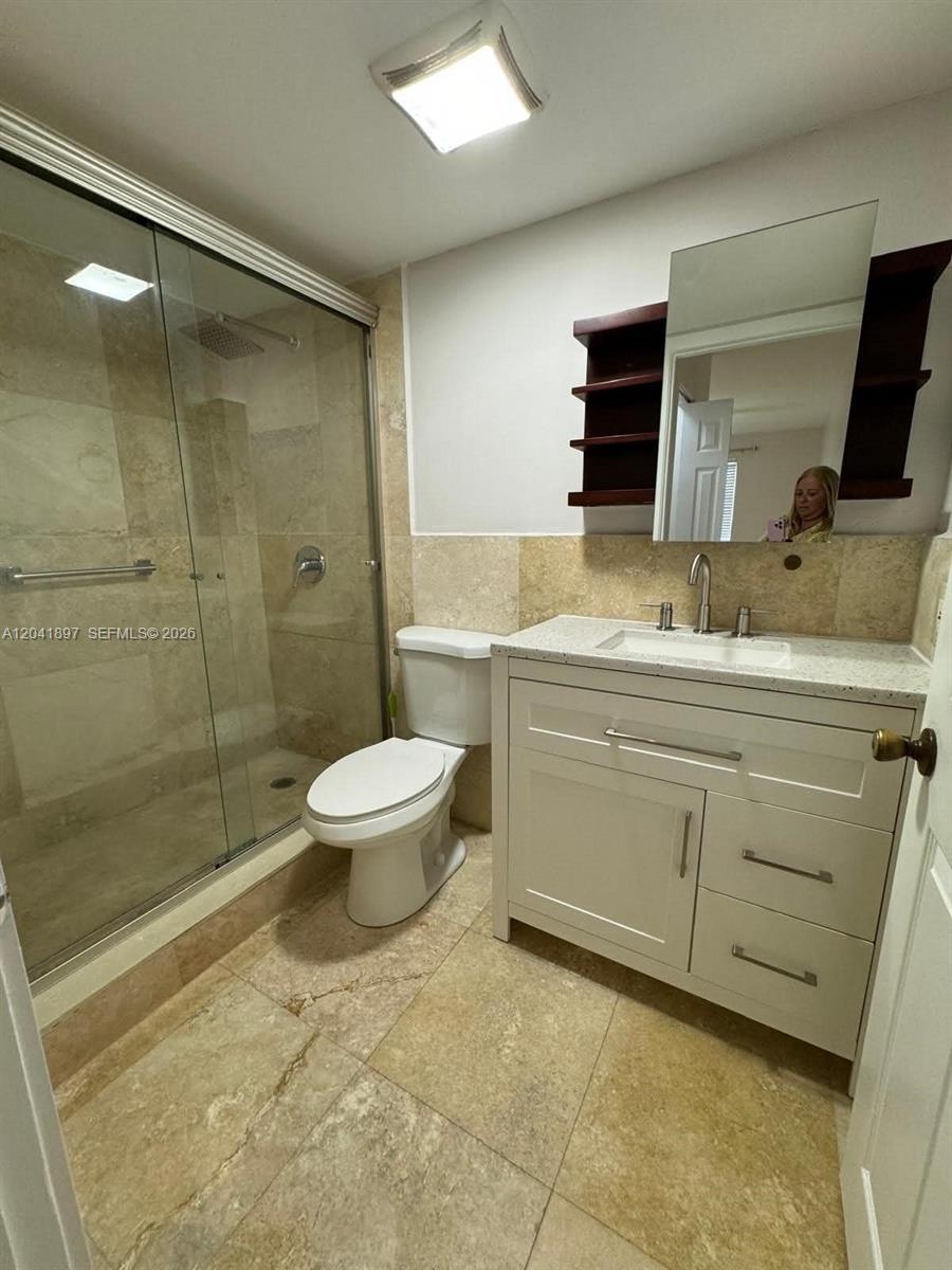 A bathroom features a glass-enclosed shower, a white vanity, and light-colored stone tile flooring — 6200 SW 131st Ct # 201, Miami FL 33183, MIAMI, FL