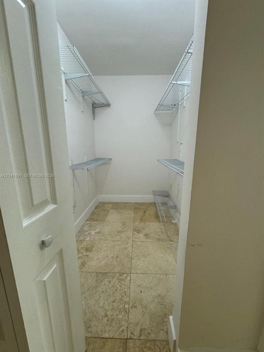 A walk-in closet features white wire shelving, beige tile flooring, and white walls — 6200 SW 131st Ct # 201, Miami FL 33183, MIAMI, FL