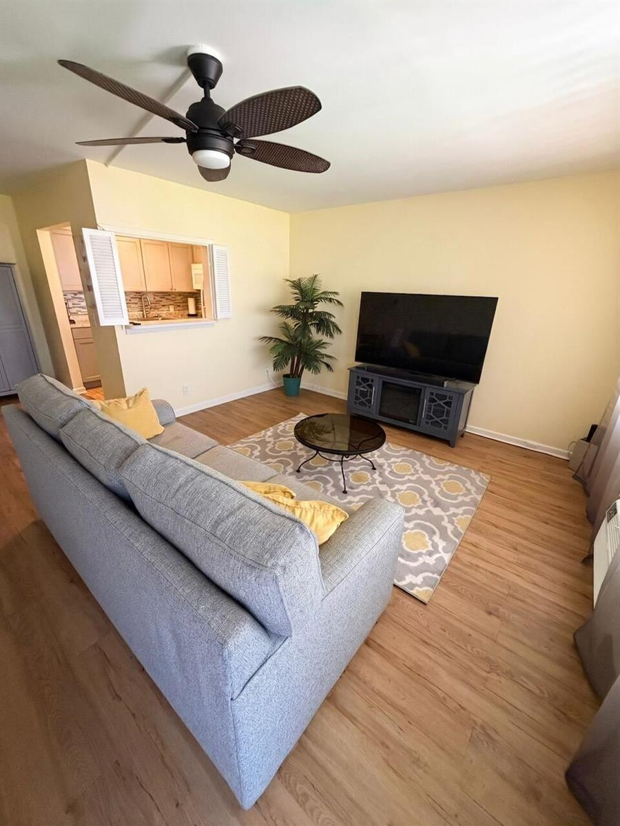 A living room features a gray sofa, a television on a stand, and a ceiling fan — 68 Brighton B, Boca Raton FL 33434, BOCA RATON, FL