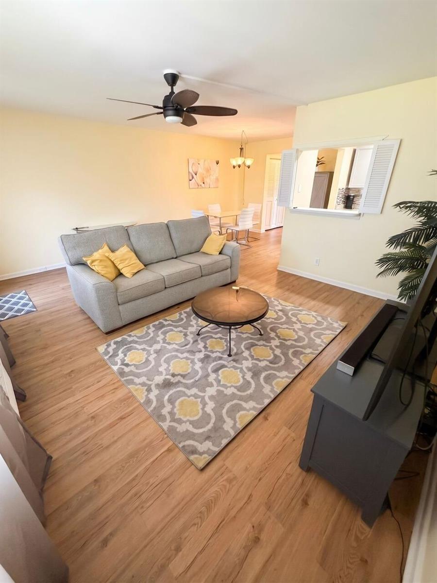 A living room features a grey sofa, a patterned rug, and light wood-look flooring — 68 Brighton B, Boca Raton FL 33434, BOCA RATON, FL