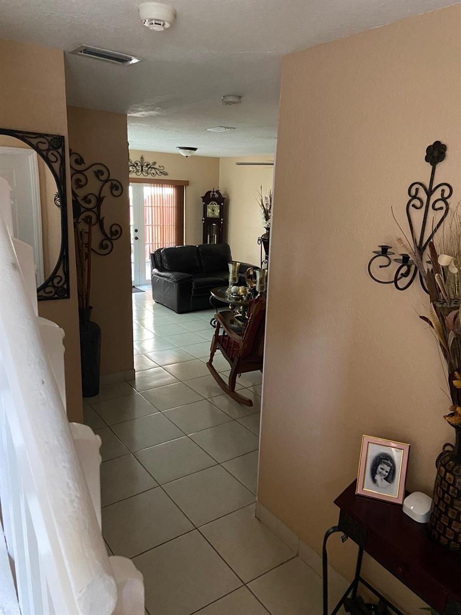 A view from a hallway into a living room with tile floors and a rocking chair — 8752 NW 107th Terrace # 8752, Hialeah Gardens FL 33018, HIALEAH GARDENS, FL