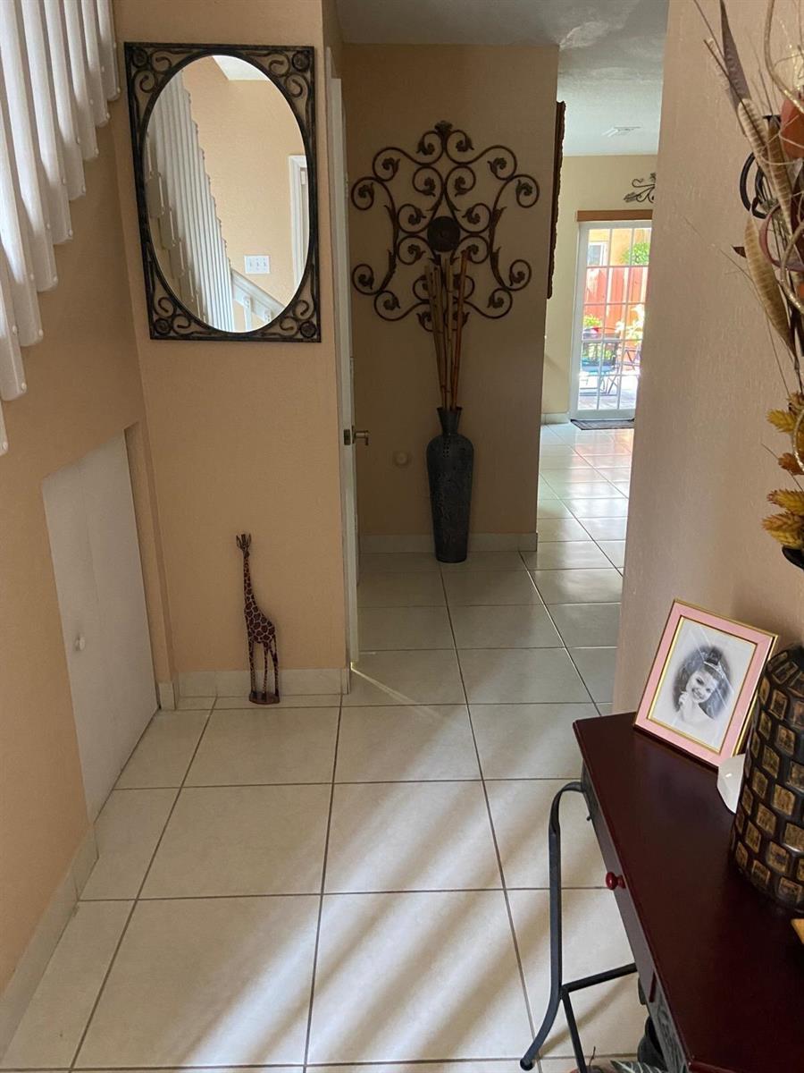 A tiled hallway features a mirror, a giraffe figurine, wall decor, and a console table — 8752 NW 107th Terrace # 8752, Hialeah Gardens FL 33018, HIALEAH GARDENS, FL