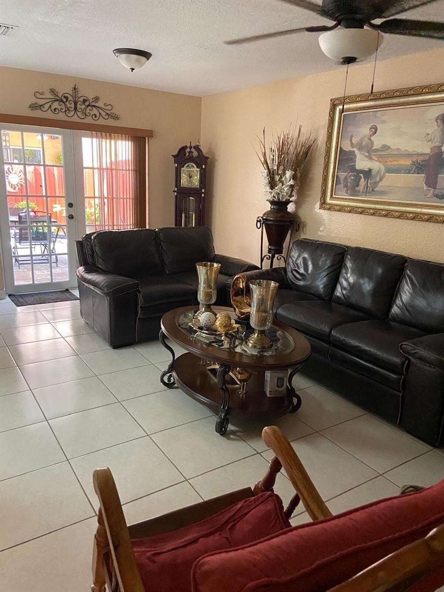 A living room features dark leather sofas, a glass-topped coffee table, and tile flooring — 8752 NW 107th Terrace # 8752, Hialeah Gardens FL 33018, HIALEAH GARDENS, FL
