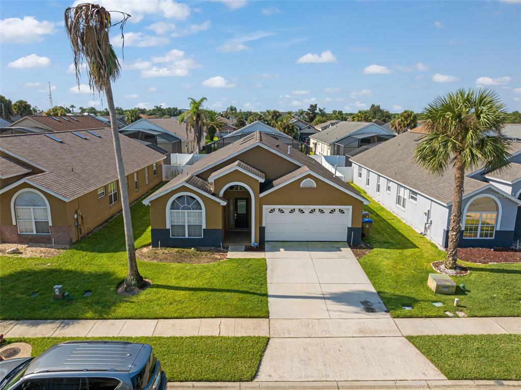 An elevated view of a tan single-story suburban house with a two-car garage and lawn — 8060 SANTEE DRIVE, KISSIMMEE, FL