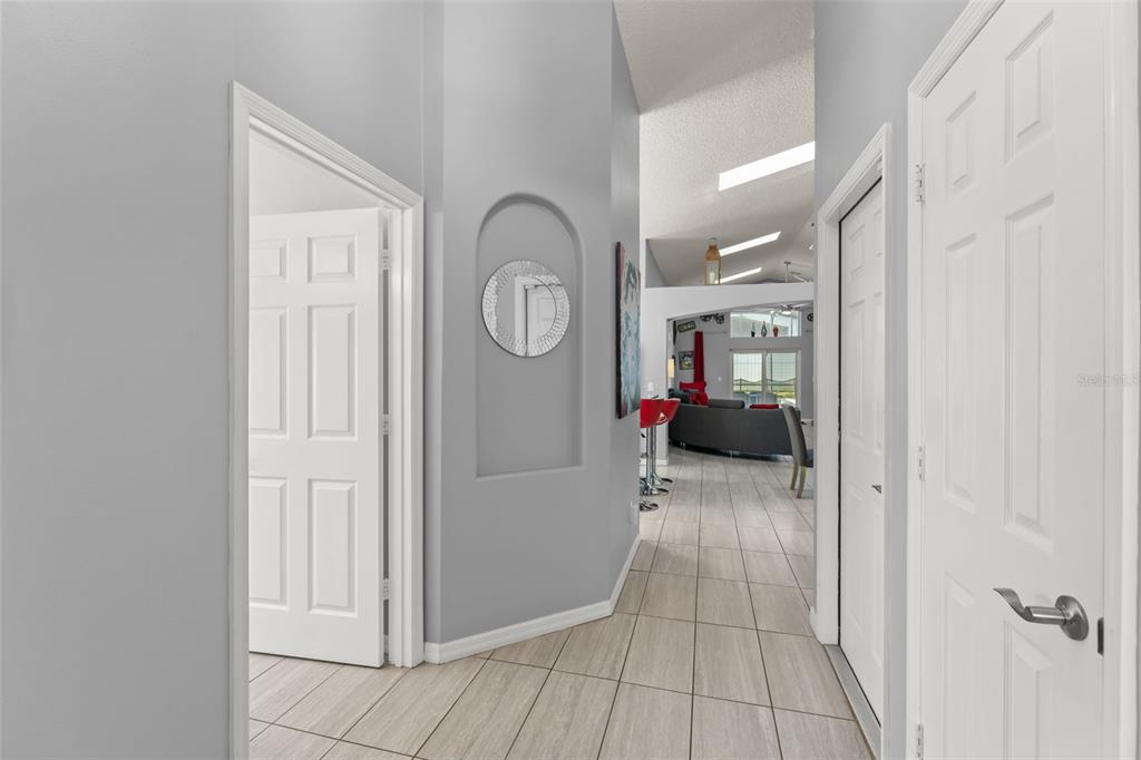 A hallway with light tile floors leads toward an open living area with vaulted ceilings — 8060 SANTEE DRIVE, KISSIMMEE, FL
