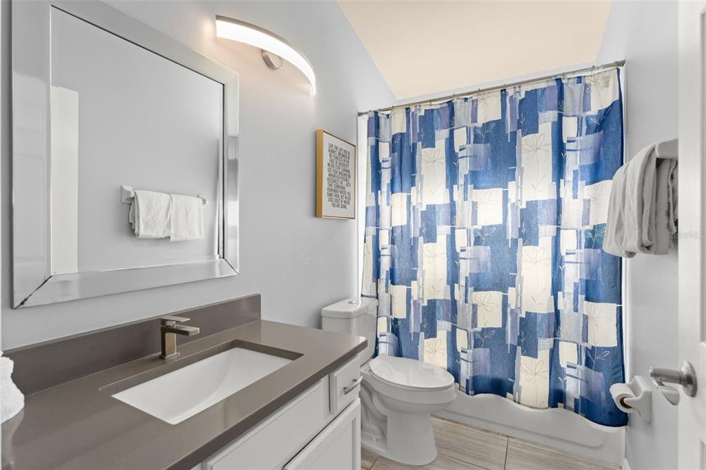 A bathroom with a gray vanity, a white sink, a mirror, and a blue patterned shower curtain — 8060 SANTEE DRIVE, KISSIMMEE, FL