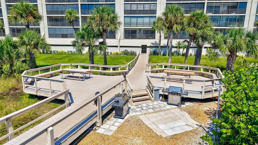 An outdoor apartment hallway features tiled flooring, a metal railing, and multiple unit doors — 420 BEACH ROAD UNIT 508, SARASOTA, FL