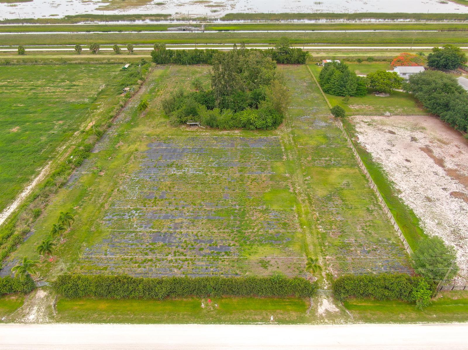 An aerial view shows a rectangular plot of land with a central wooded area — 16295 Rustic Road, Wellington FL 33470, WELLINGTON, FL