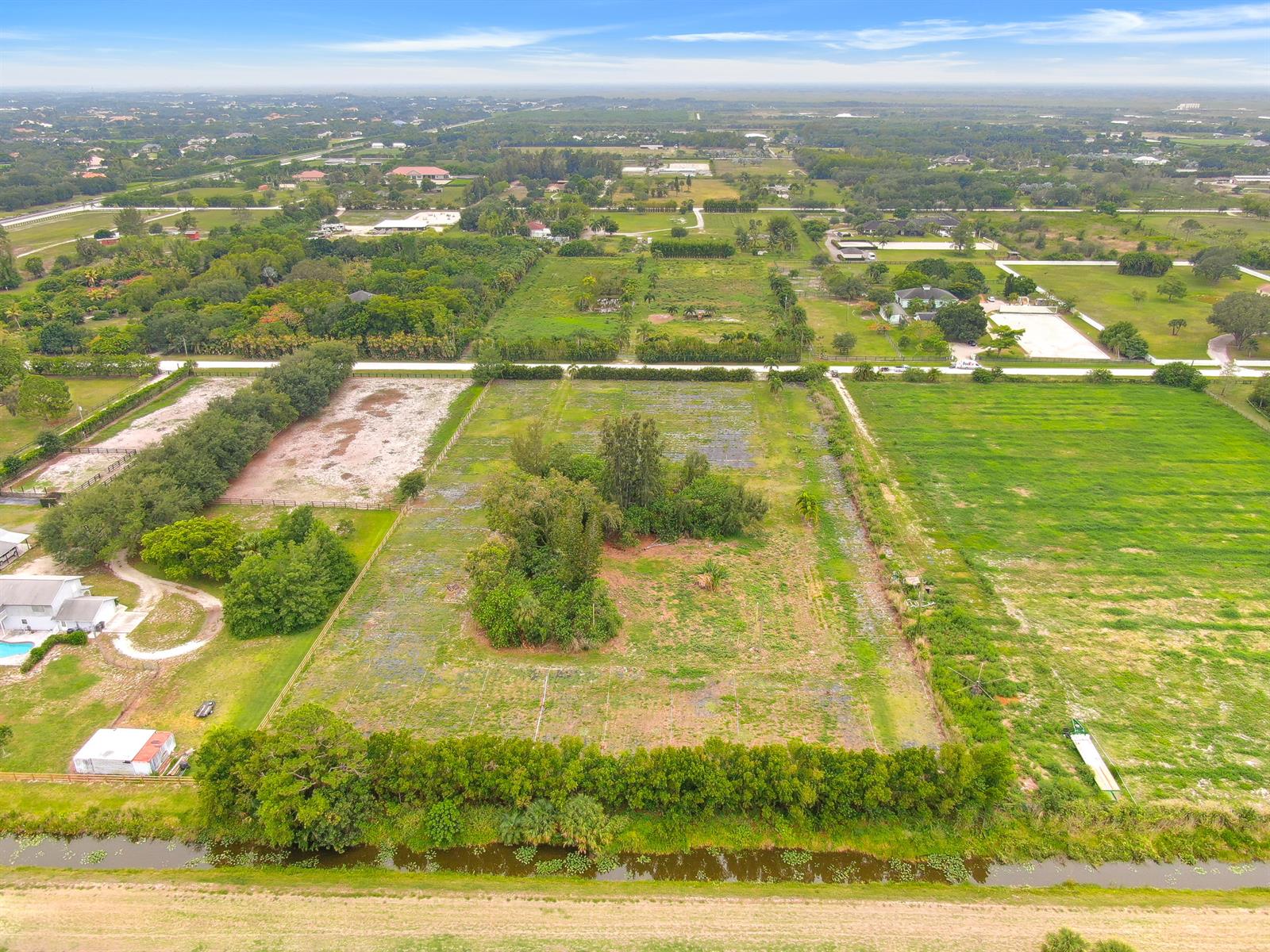 An aerial view shows a rectangular plot of land with trees and a drainage canal — 16295 Rustic Road, Wellington FL 33470, WELLINGTON, FL