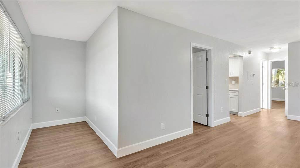 A room with light gray walls, wood-look flooring, and a doorway leading to a kitchen — 5900 22ND AVENUE N UNIT 14, ST PETERSBURG, FL