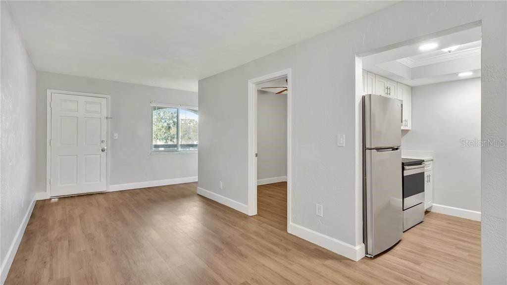 A living area with wood-look flooring leads to a kitchen with stainless steel appliances — 5900 22ND AVENUE N UNIT 14, ST PETERSBURG, FL