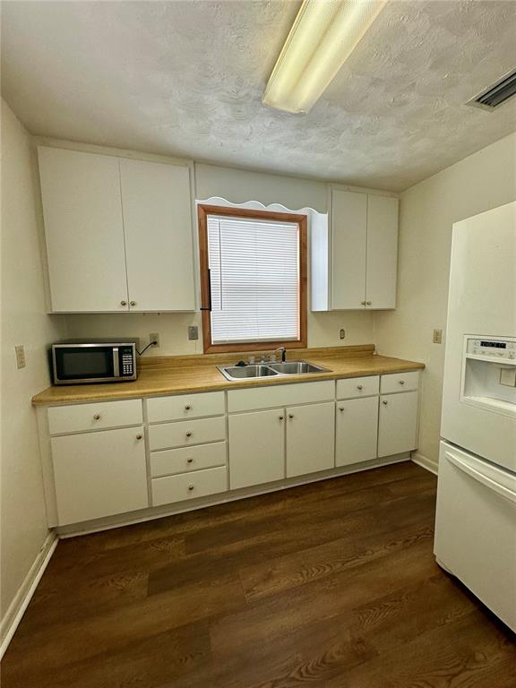 A kitchen features white cabinets, a wood-look floor, a double sink, and a microwave — 520 SW 5TH AVENUE, LAKE BUTLER, FL