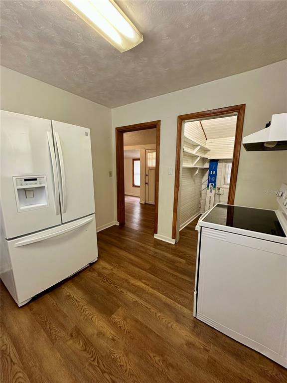 A kitchen features white appliances, wood-look flooring, and two doorways leading to other rooms — 520 SW 5TH AVENUE, LAKE BUTLER, FL